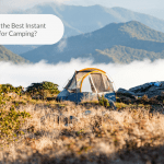 Photo of a tent in the middle of a scenic highland with a view of mountains behind