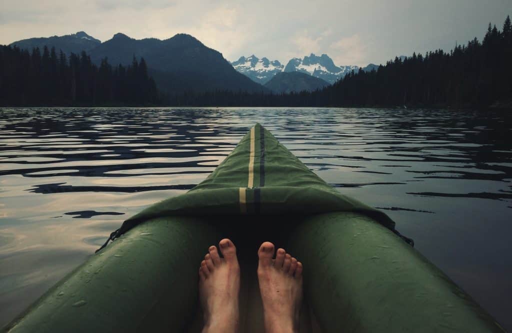 Photo of Kayak with pair of legs on a lake floating