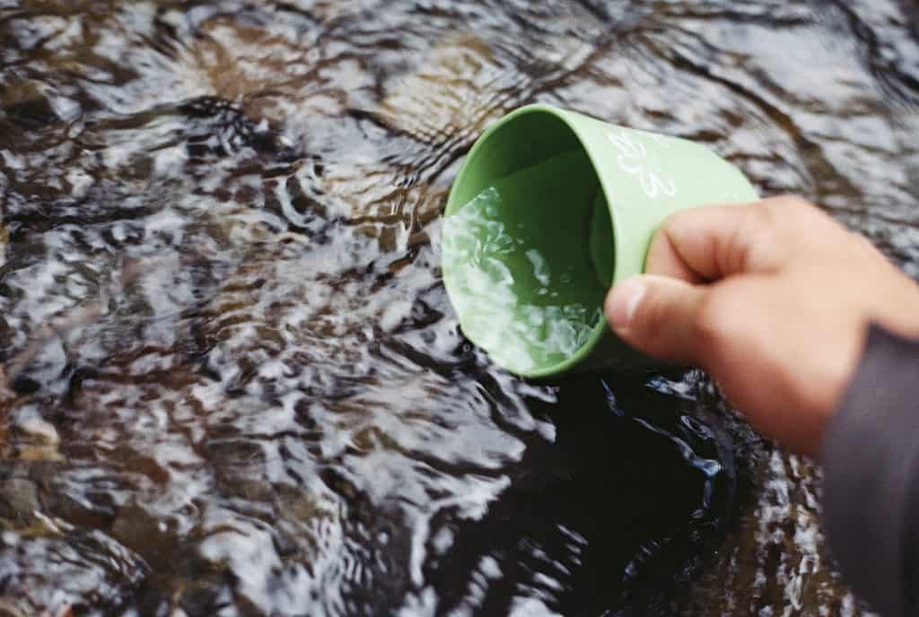 Photo of Camping mug getting water from fresh water lake