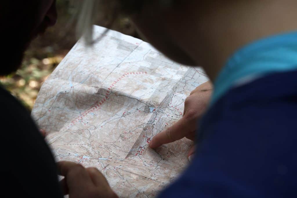 Over The Shoulder Shot Of 2 Guys Looking At A Topo Map