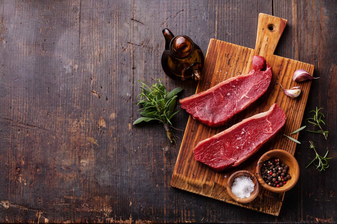 Raw fresh meat Striploin steak and seasoning on dark wooden background
