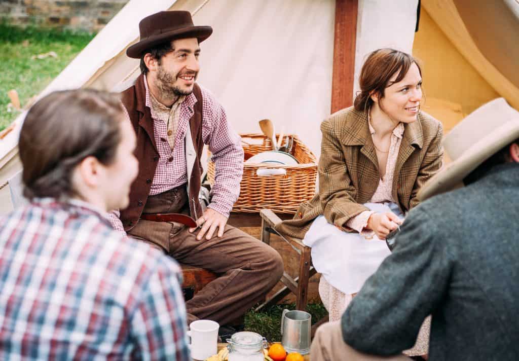 Group of people beside a tent waiting for something