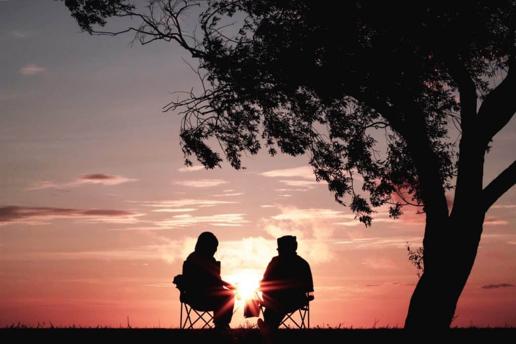 Two persons sitting and watching sunset
